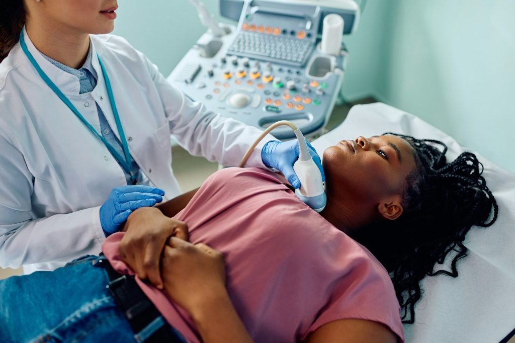 Black woman during ultrasound diagnostics of endocrine system and thyroid at medical clinic.