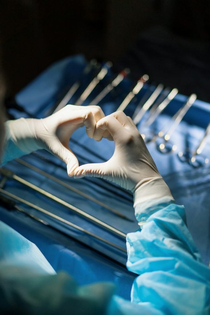 the doctor shows the heart sign with his hands after the operation on of surgical instruments